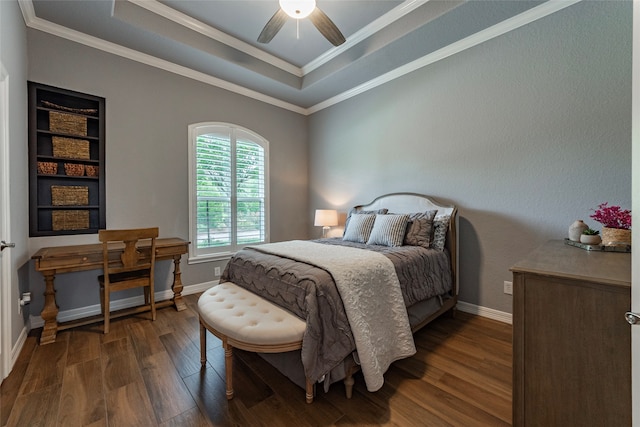 bedroom with dark wood-type flooring, a tray ceiling, ceiling fan, and crown molding