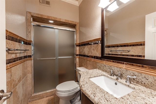 bathroom featuring crown molding, tile walls, toilet, and a shower with shower door