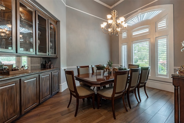 dining area with dark wood-type flooring, a chandelier, and crown molding