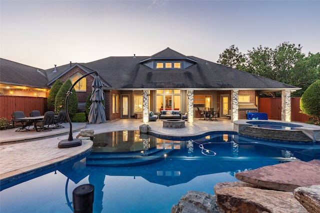 pool at dusk featuring an in ground hot tub, outdoor lounge area, and a patio area