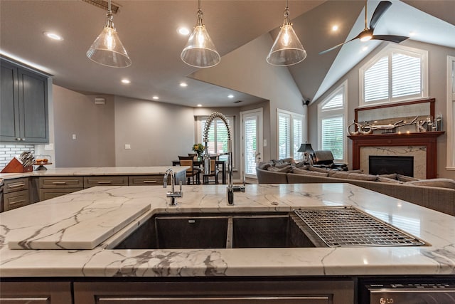 kitchen featuring plenty of natural light, light stone countertops, a premium fireplace, and decorative light fixtures