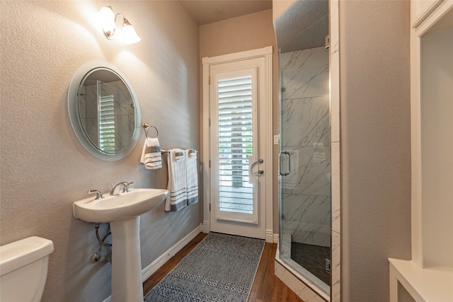 bathroom featuring a shower with door, toilet, and wood-type flooring