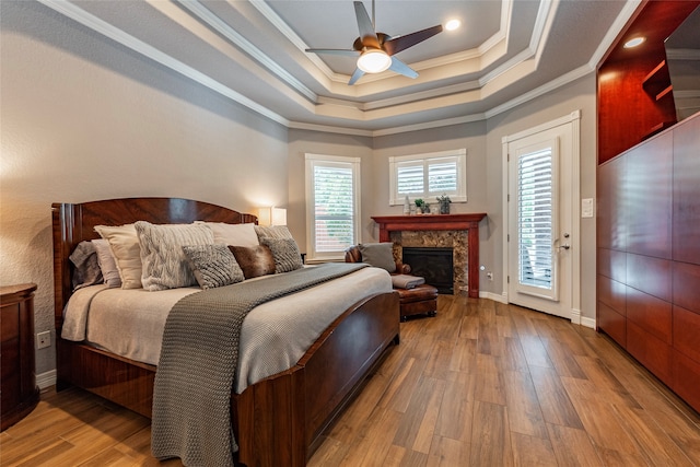 bedroom with hardwood / wood-style floors, crown molding, a premium fireplace, access to exterior, and ceiling fan