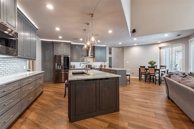 kitchen featuring a center island with sink, a breakfast bar, appliances with stainless steel finishes, and light hardwood / wood-style floors