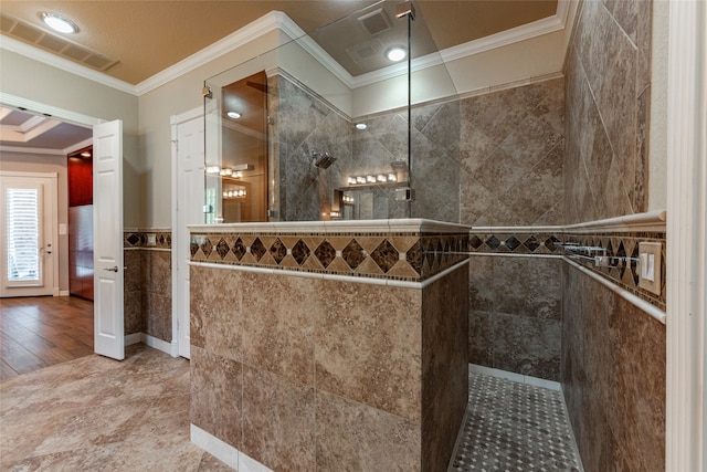 bathroom featuring hardwood / wood-style floors, a tile shower, tile walls, and ornamental molding