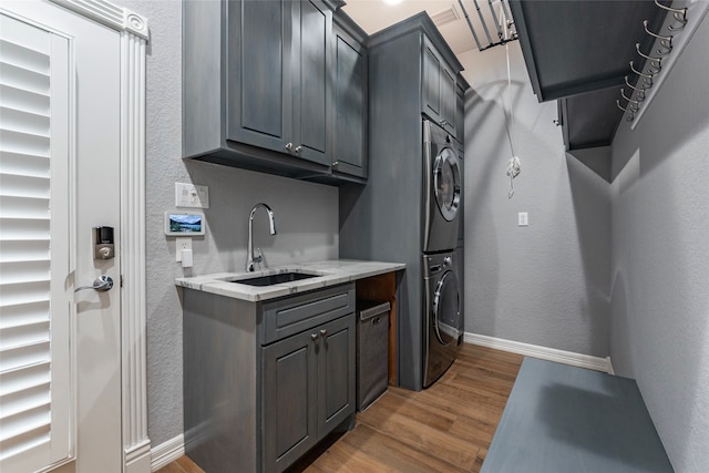 kitchen featuring dark hardwood / wood-style floors, sink, stacked washer / dryer, and gray cabinetry