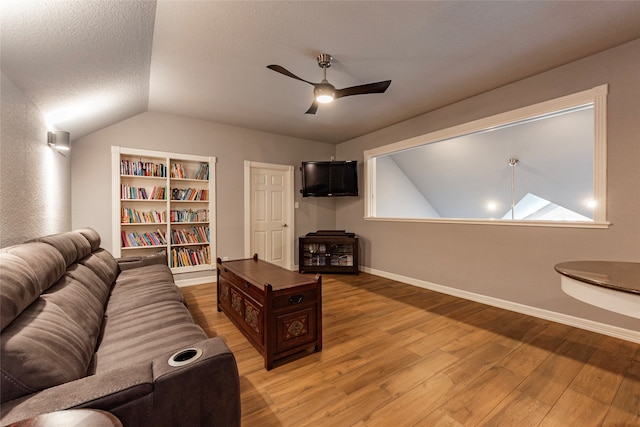 living room featuring built in shelves, a textured ceiling, wood-type flooring, ceiling fan, and lofted ceiling