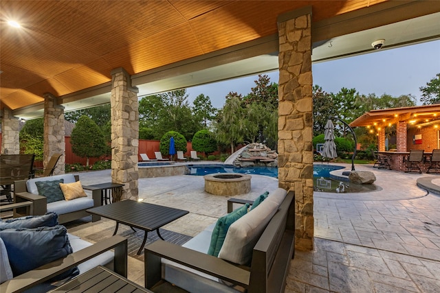 patio terrace at dusk featuring an outdoor living space with a fire pit and a swimming pool with hot tub