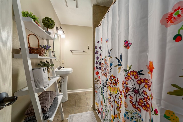 bathroom featuring a shower with shower curtain, a sink, baseboards, and tile patterned floors