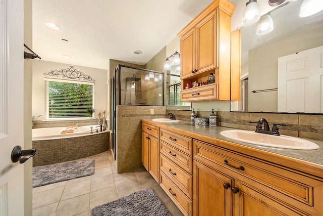 bathroom featuring a bath, a stall shower, tile patterned flooring, and a sink