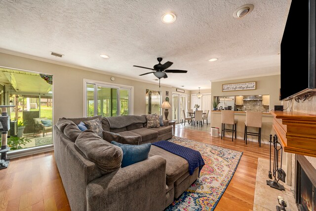 living area featuring ceiling fan, recessed lighting, visible vents, ornamental molding, and light wood finished floors