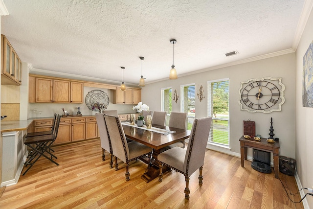 dining space featuring ornamental molding, light wood finished floors, and visible vents