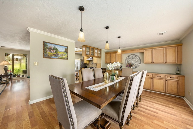 dining space featuring baseboards, crown molding, light wood-style flooring, and a textured ceiling