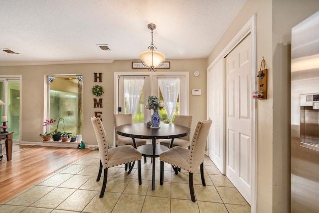 dining room featuring a textured ceiling, light tile patterned floors, and visible vents