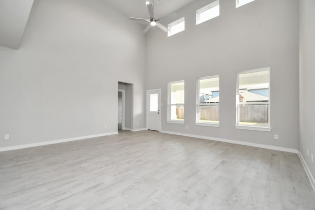 unfurnished living room with a high ceiling, ceiling fan, and light hardwood / wood-style flooring