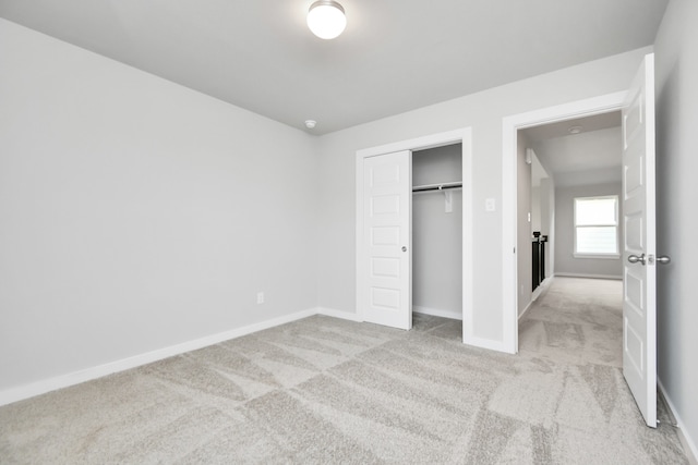 unfurnished bedroom with light colored carpet and a closet