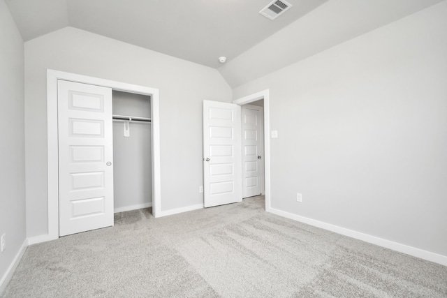 unfurnished bedroom featuring vaulted ceiling, a closet, and light carpet