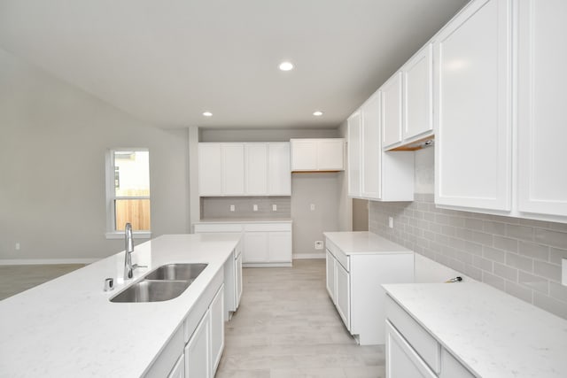 kitchen with light stone countertops, white cabinetry, tasteful backsplash, and sink