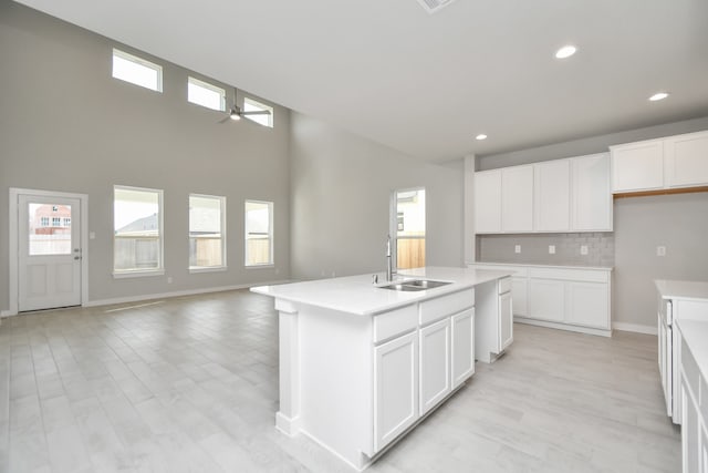 kitchen featuring a center island with sink, ceiling fan, sink, white cabinetry, and tasteful backsplash