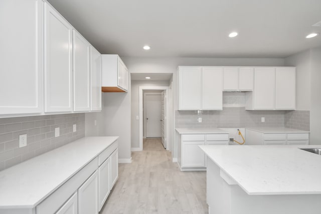 kitchen with white cabinets, light hardwood / wood-style floors, and decorative backsplash