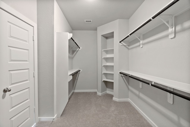 walk in closet with light colored carpet