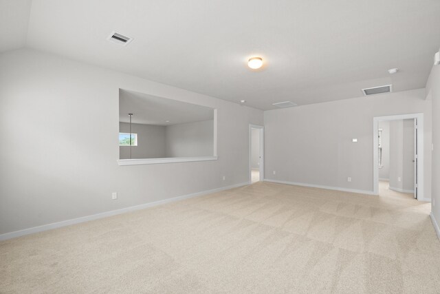 empty room featuring vaulted ceiling and light colored carpet