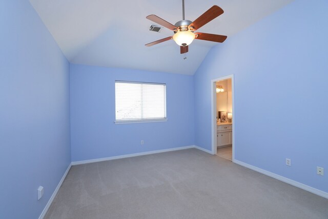 unfurnished bedroom featuring baseboards, light colored carpet, ensuite bathroom, and lofted ceiling