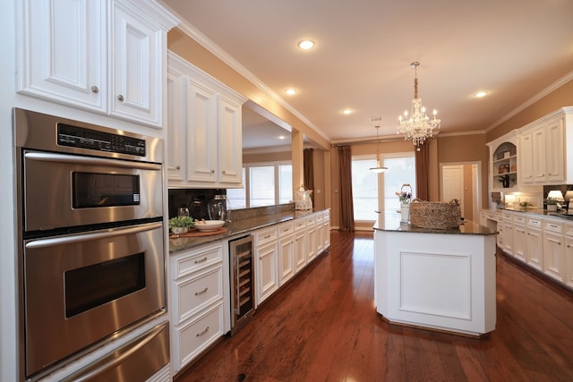 kitchen with stainless steel double oven, an inviting chandelier, a center island, ornamental molding, and a warming drawer