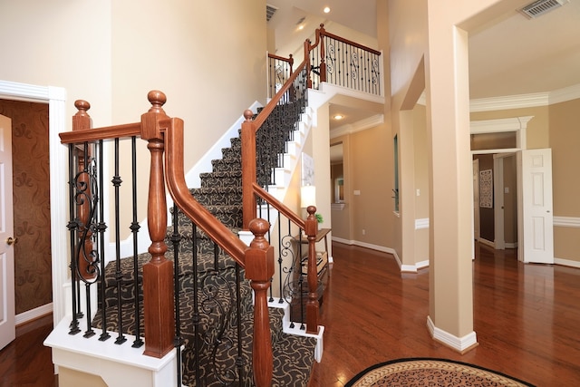 stairs featuring visible vents, baseboards, crown molding, and wood finished floors
