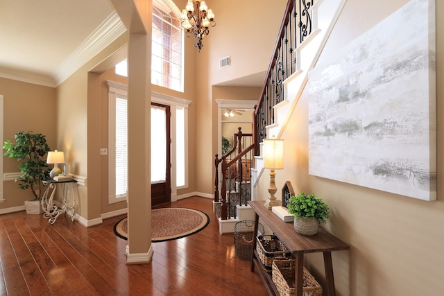 entryway featuring crown molding, a notable chandelier, wood finished floors, visible vents, and stairway