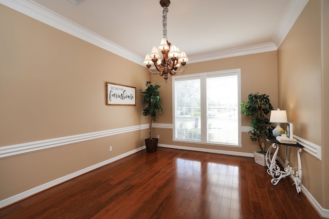 spare room with an inviting chandelier, baseboards, ornamental molding, and hardwood / wood-style flooring