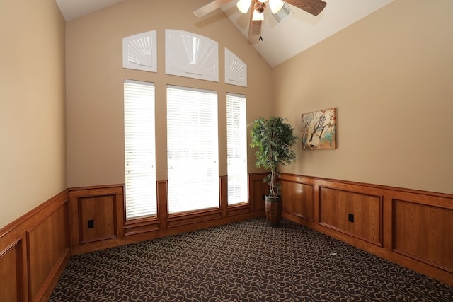 spare room featuring wainscoting, a decorative wall, dark carpet, a ceiling fan, and visible vents