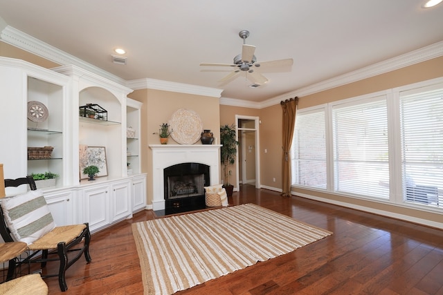 living area with a ceiling fan, dark wood-style flooring, visible vents, a fireplace, and ornamental molding