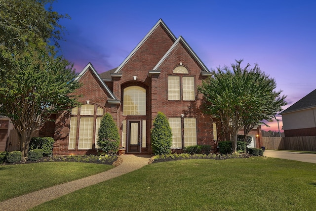 traditional-style home featuring fence, a front yard, and brick siding