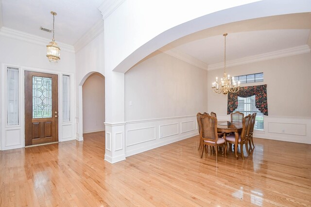 dining space with ornamental molding, light hardwood / wood-style flooring, and a notable chandelier