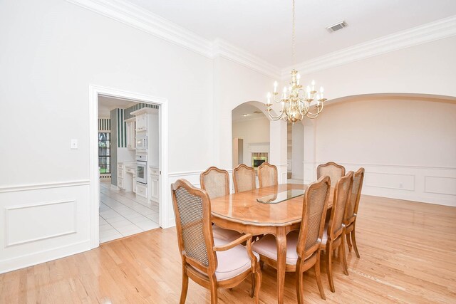 dining space featuring light wood-type flooring, a chandelier, and crown molding