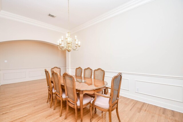 dining room featuring ornamental molding, an inviting chandelier, and light hardwood / wood-style floors