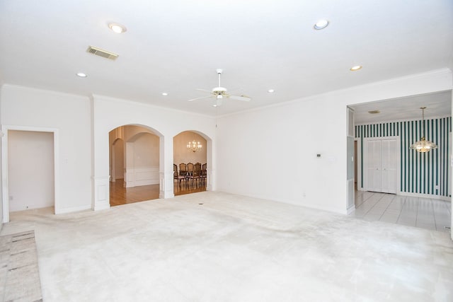 unfurnished living room with ceiling fan with notable chandelier, light colored carpet, and crown molding