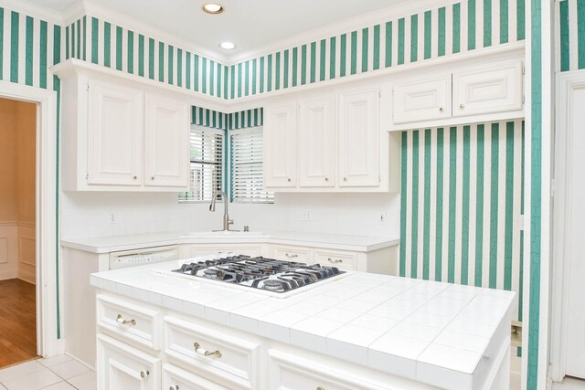 kitchen with stainless steel gas cooktop, tile countertops, light hardwood / wood-style flooring, a center island, and sink