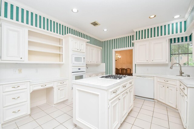 kitchen featuring white appliances, a center island, sink, white cabinetry, and light tile patterned flooring