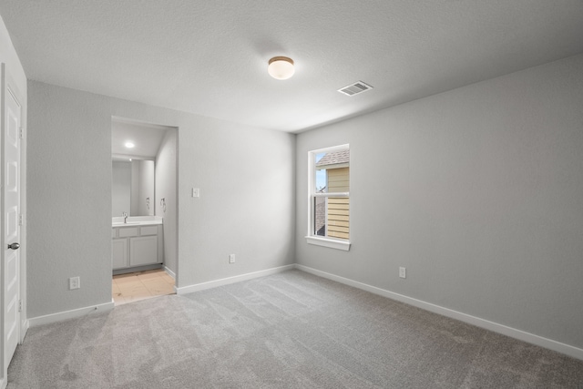 spare room featuring light carpet, a textured ceiling, and sink