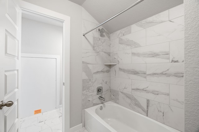 bathroom with lofted ceiling, tiled shower / bath combo, and a textured ceiling