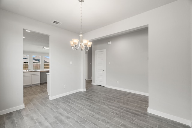 unfurnished dining area with a chandelier and light hardwood / wood-style floors