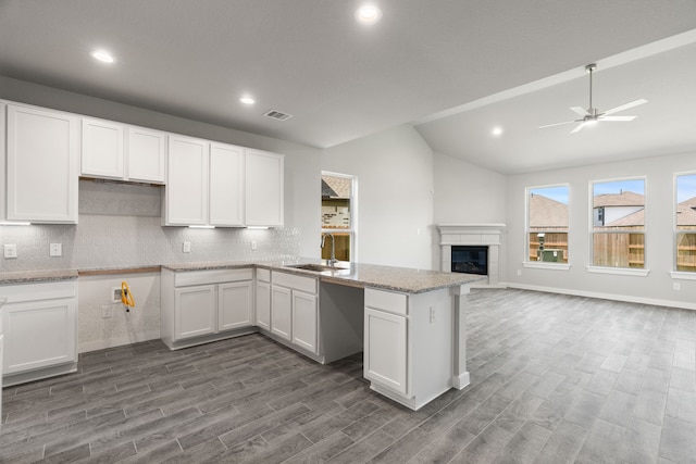 kitchen with ceiling fan, sink, vaulted ceiling, and white cabinets