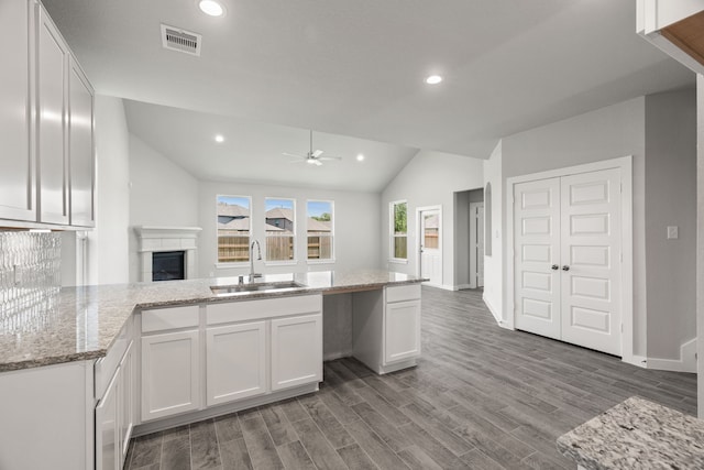 kitchen with white cabinetry, sink, ceiling fan, lofted ceiling, and hardwood / wood-style flooring