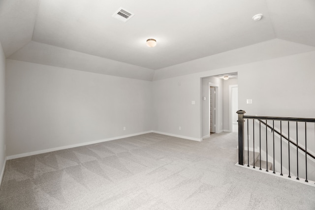 spare room featuring vaulted ceiling and light colored carpet