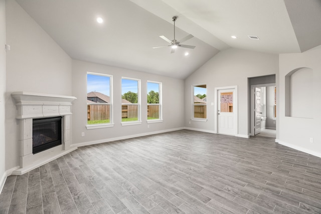 8427 Northern Pintail Dr, Houston, TX 77049 - unfurnished living room with baseboards, ceiling fan, wood finished floors, a glass covered fireplace, and vaulted ceiling