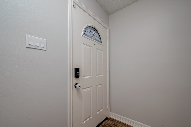 doorway with a textured ceiling and hardwood / wood-style floors