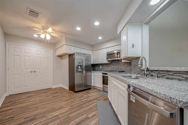 kitchen featuring light wood-type flooring, white cabinetry, tasteful backsplash, stainless steel appliances, and sink