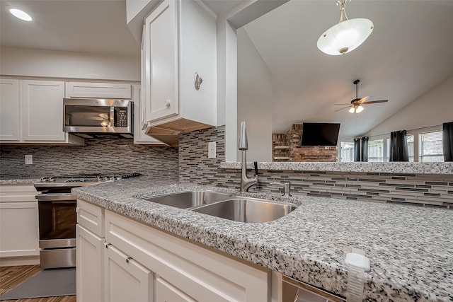 kitchen featuring vaulted ceiling, backsplash, stainless steel appliances, and ceiling fan